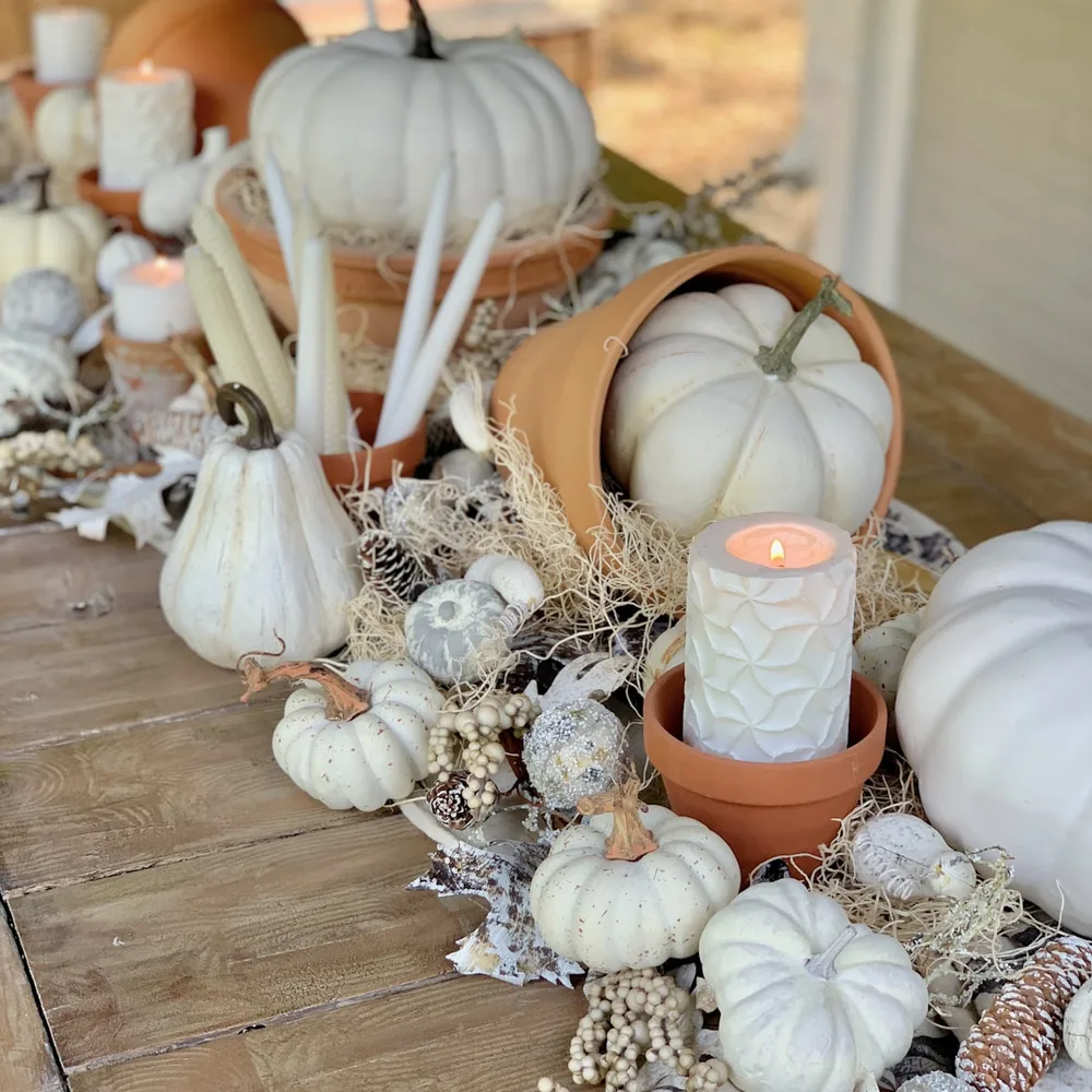 Chemin de table automnal avec bougies blanches et petites citrouilles