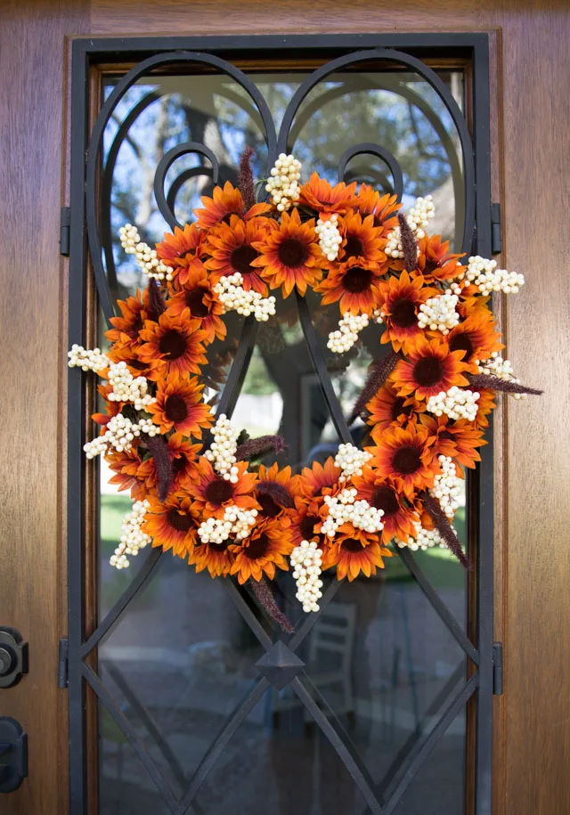 Couronne d’automne fleurie orange et crème sur une porte