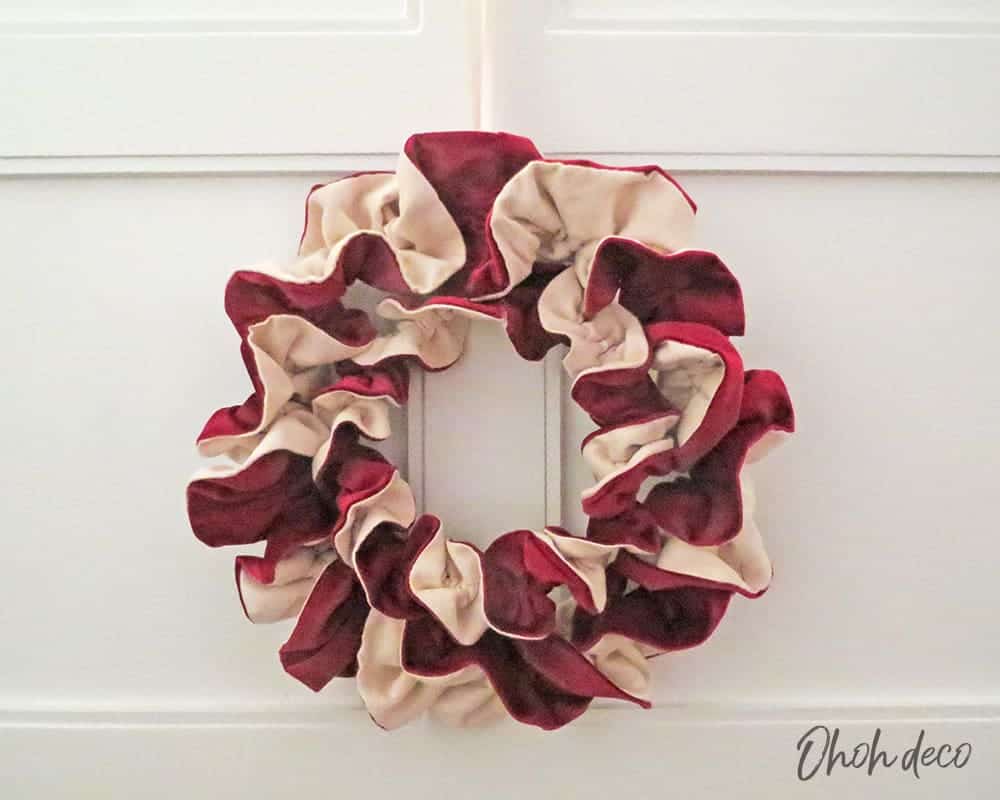 Couronne de Noël volumineuse réalisée avec des bandes de tissu rouge et crème