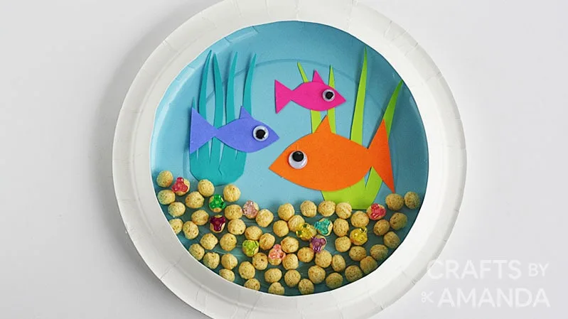 Aquarium miniature avec poissons en papier dans une assiette en carton