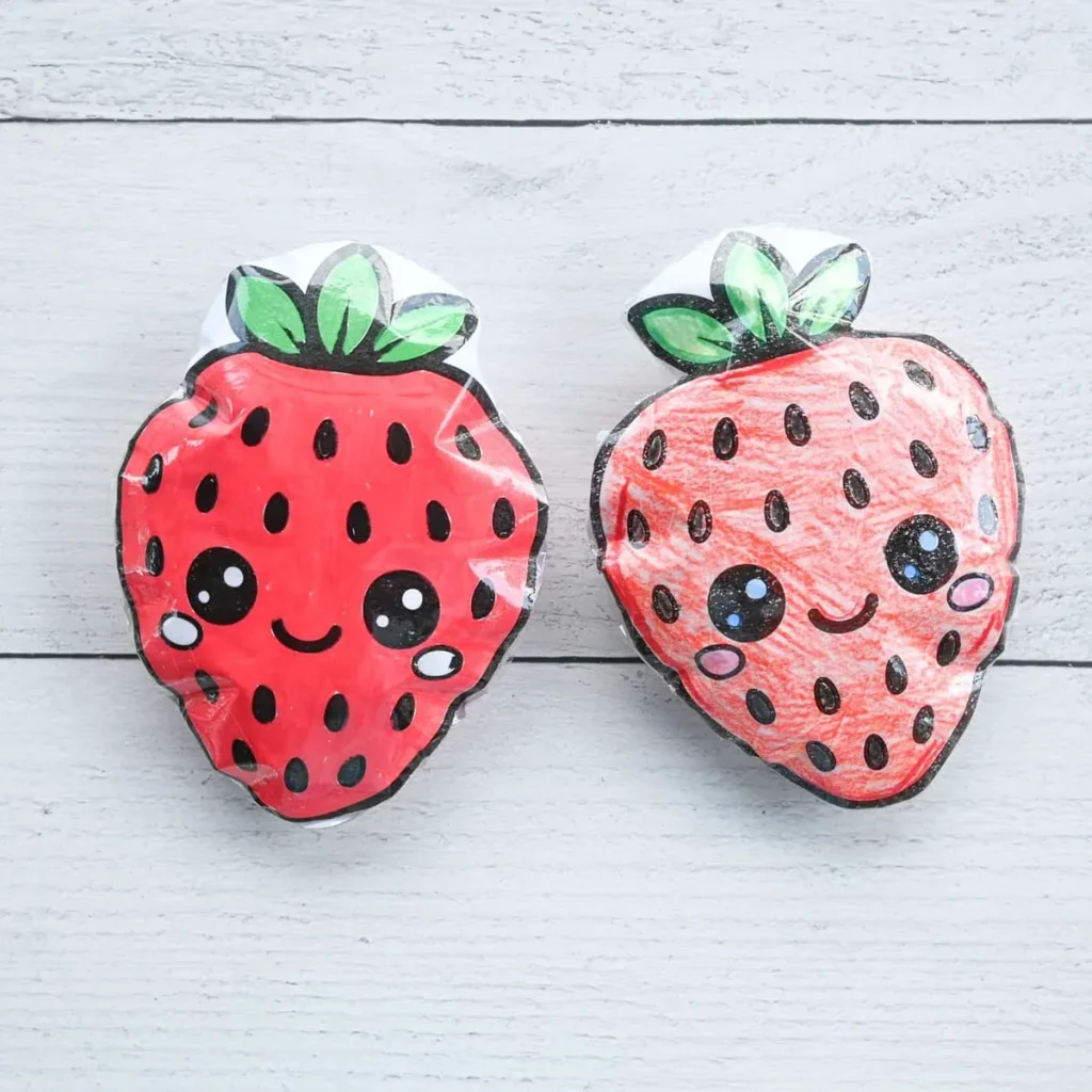 Deux squishies en papier en forme de fraise avec des visages dessinés
