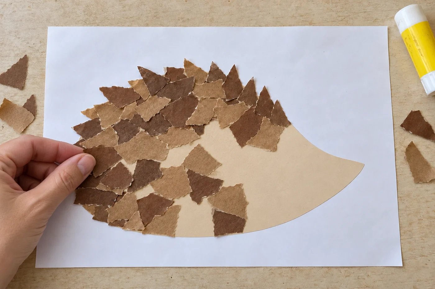 Collage en cours de petits morceaux bruns sur le dos du hérisson, avec des zones beiges encore visibles