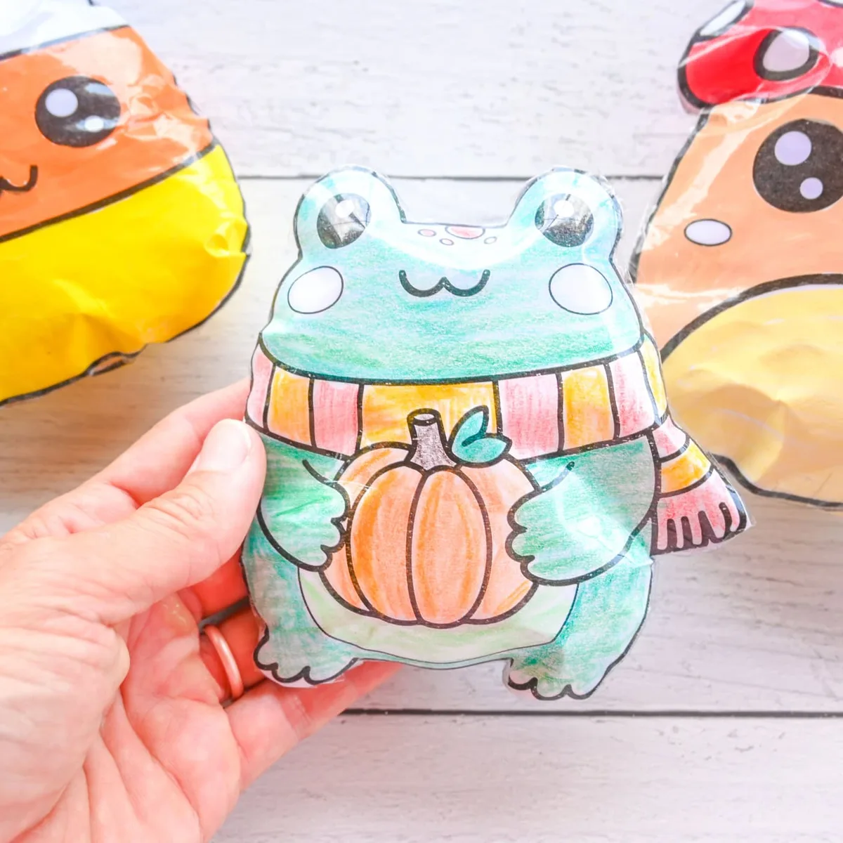 Grenouille en papier dessinée sur un squishy, entourée de petites formes automnales